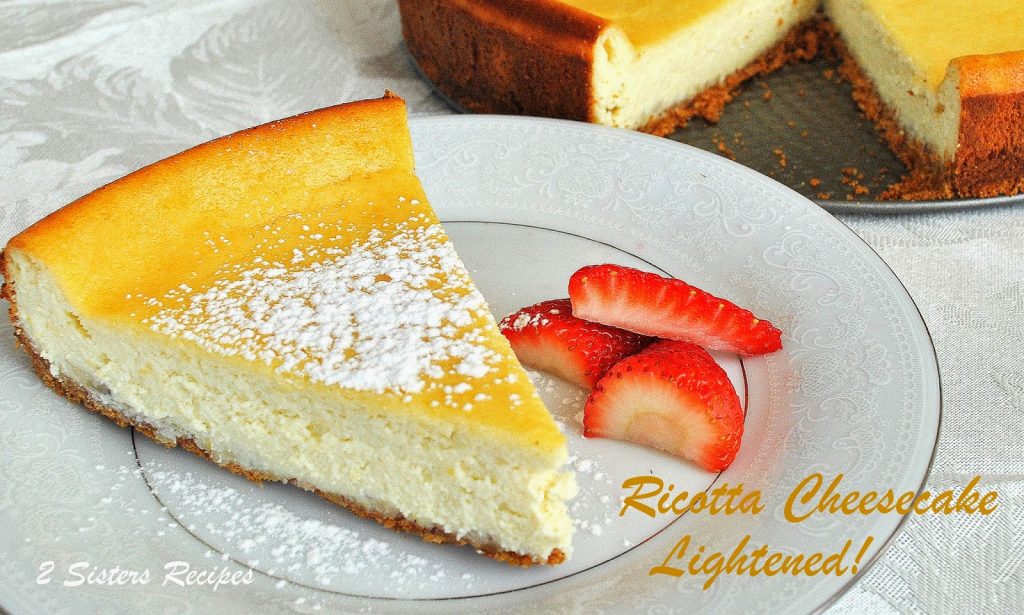A slice of ricotta cheesecake is served on a plate with sliced strawberries on the side. 