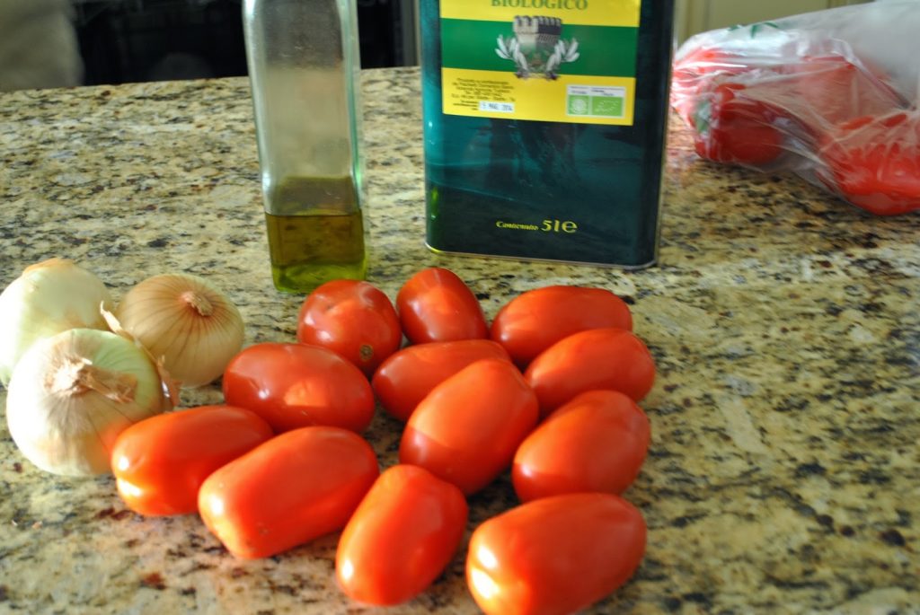 A photo of fresh Roman tomatoes, olive oil and onions on the counter. by 2sistersrecipes.com 