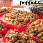 A glass baking dish filled with red peppers stuffed with crumbled sausages.