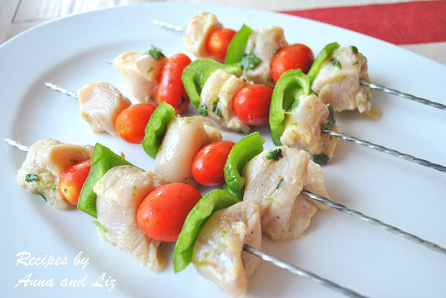 Skewers filled with pieces of chicken and veggies on a white platter.  by 2sistersrecipes.com