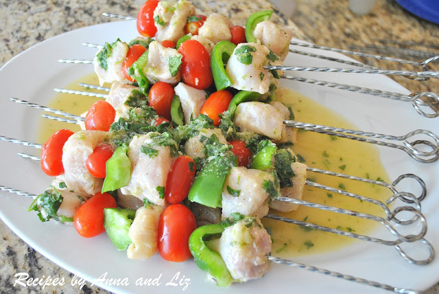 Raw pieces of chicken with vegetables on a long skewer marinating on a white platter. by 2sistersrecipes.com