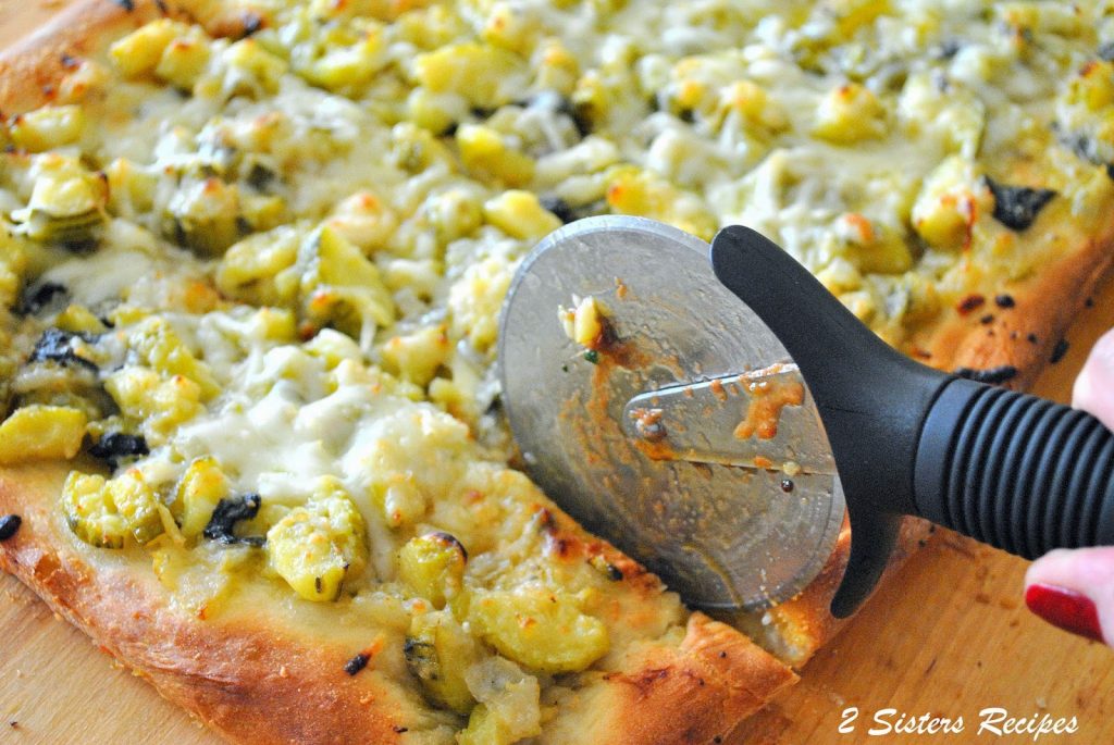 Cutting into the pizza pie with a pizza cutter. by 2sistersrecipes.com 