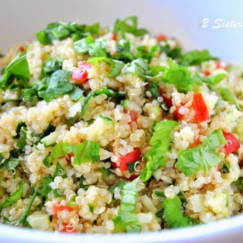 A white bowl filled with a quinoa salad, fresh parsley and minced tomatoes.