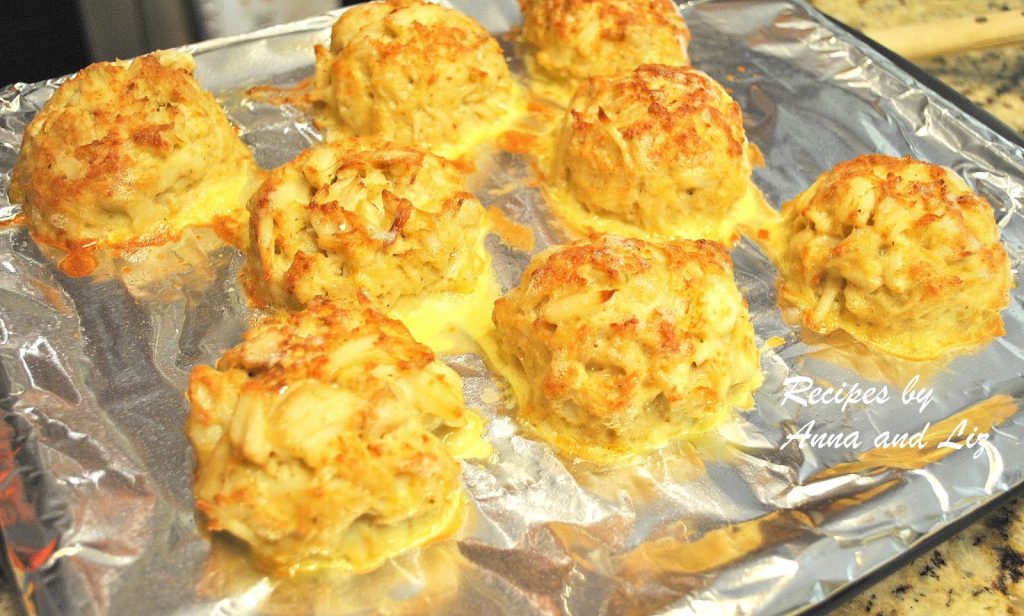 A baking sheet covered with aluminum foil with Crab cakes broiled to golden color.