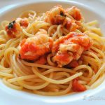 A dish with spaghetti and cooked pieces of lobster on top.