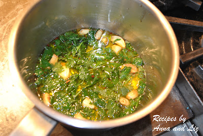 A small pot filled with oil, garlic and fresh parsley cooking on stovetop. 