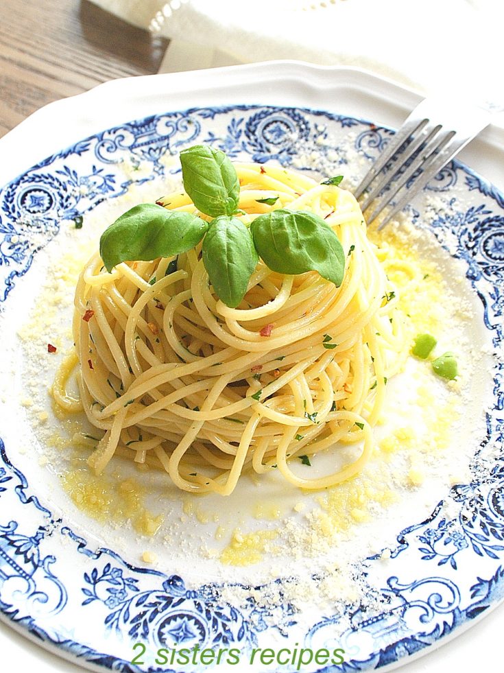 A blue and white plate with spaghetti twirled in the center with fresh basil on top.