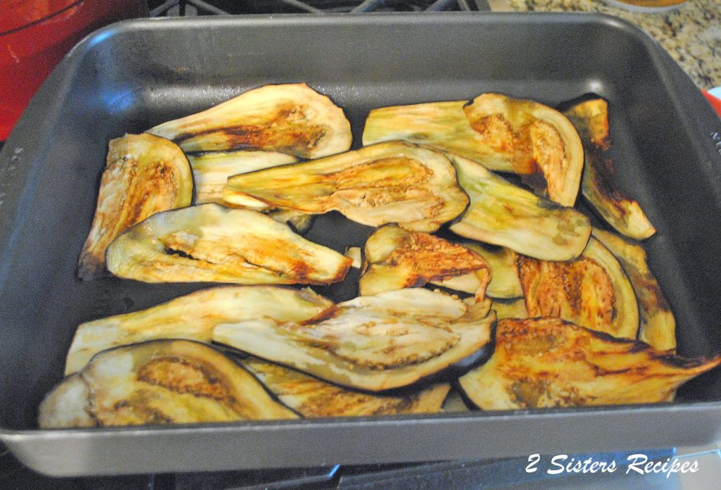 Slices of eggplants in a roasting pan. by 2sistersrecipes.com