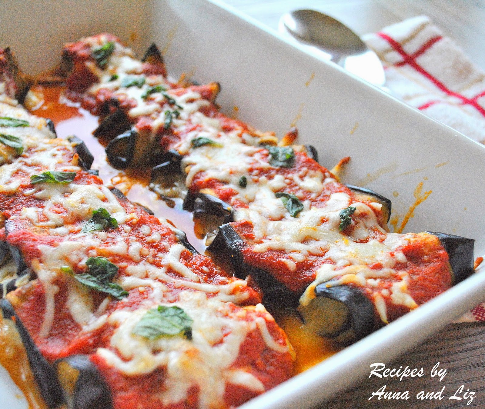 A casserole dish filled with Eggplant Rollatini topped with tomato sauce and melted cheese. by 2sistersrecipes.com