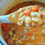 A wooden spoon filled with lima bean and carrots soup, over a pot filled with them.