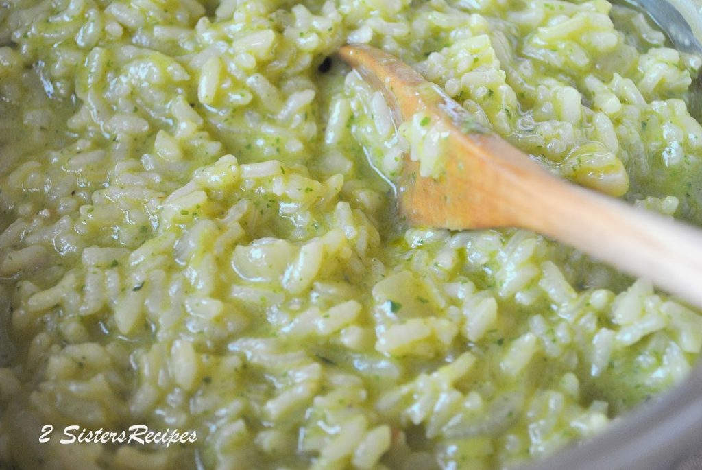 a wooden spoon stirring the pesto sauce into the risotto. by 2sistersrecipes.com 