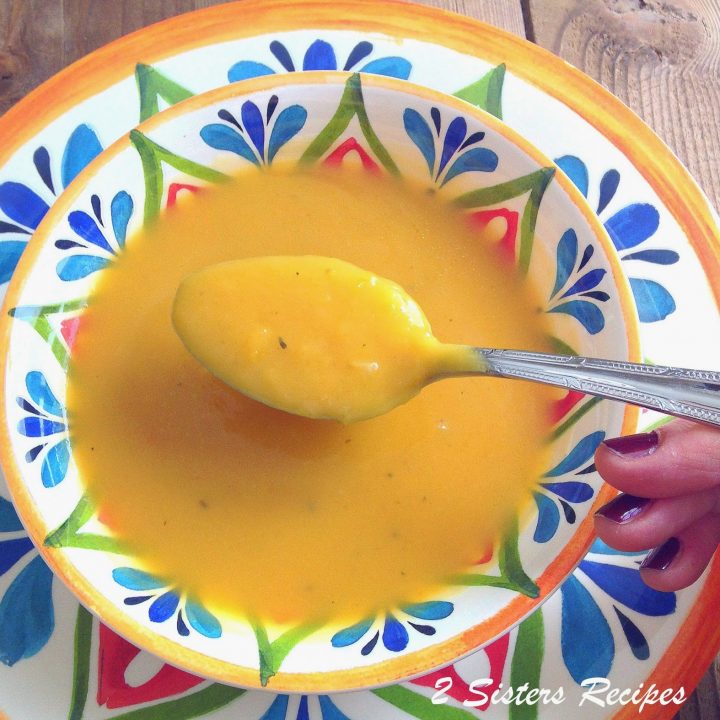 A spoonful of our creamy squash soup served in a colorful soup bowl.