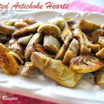 A white platter filled with roasted artichoke hearts.