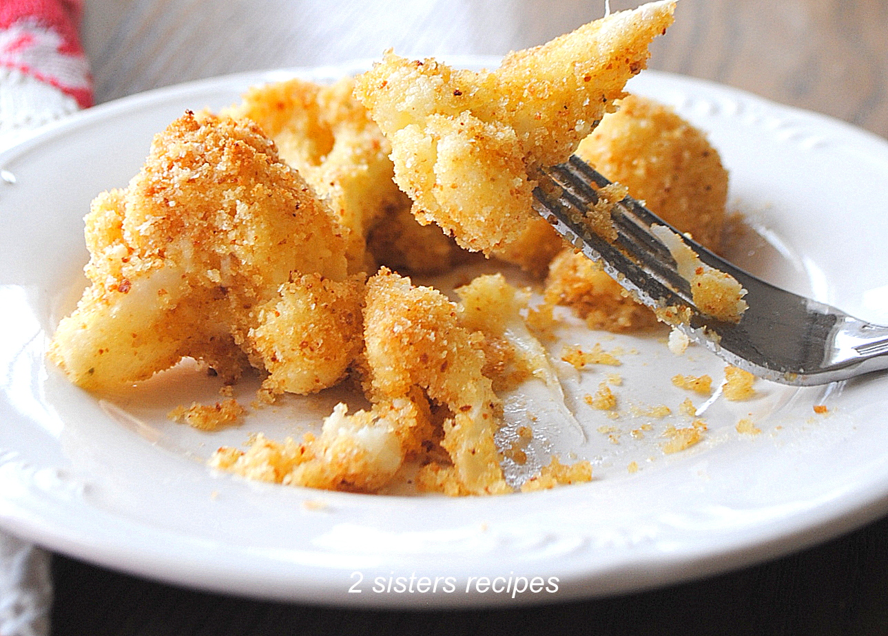 A serving of crusted pieces of roasted cauliflower au gratin on a white plate.