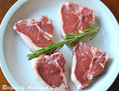 A white dish with 4 raw lamb chops and a sprig of rosemary on top.