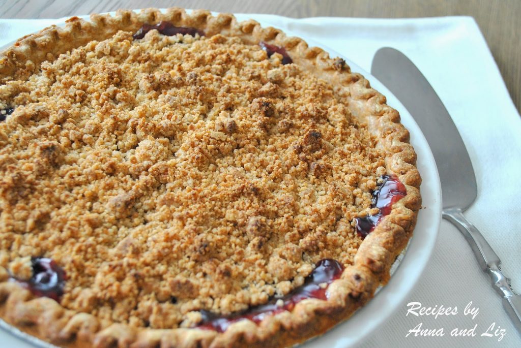A baked blueberry pie with a crumble topping served in a pie plate on the table.