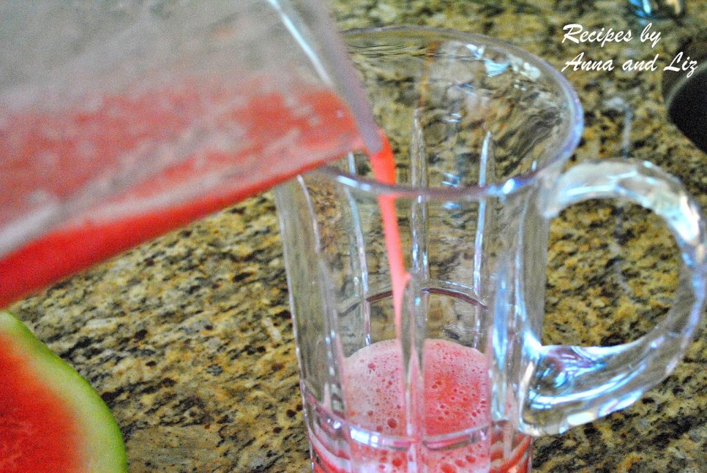 Fresh pureed watermelon and lemon mixture is poured into a glass pitcher. 