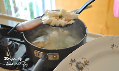 A slotted spoon draining the boiled fish over the pot. by 2sistersrecipes.com