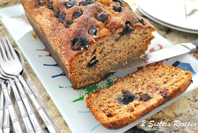 A slice of blueberry banana bread on a platter. by 2sistersrecipes.com