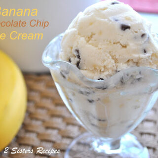A glass filled with banana ice cream with chocolate chips and a spoon inside.
