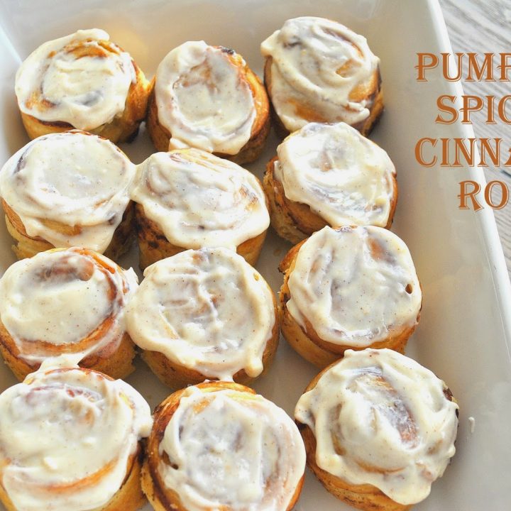 A white dish with 12 cinnamon rolls with icing on top.