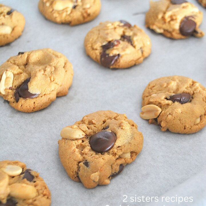 A baking sheet filled with baked peanut butter and chocolate chip cookies.