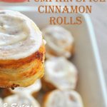 A hand holding a cinnamon roll with icing on top.