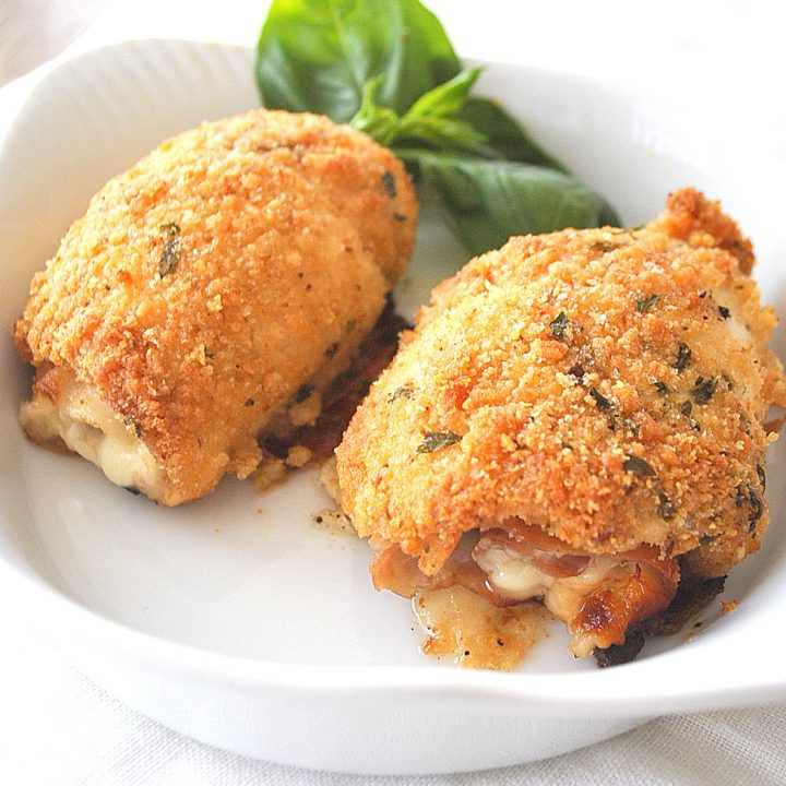 Two chicken Rollatini coated with bread crumbs and baked, served in a white dish.