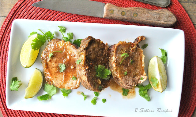 A white platter with sliced pork tenderloin with lime slices on the side.