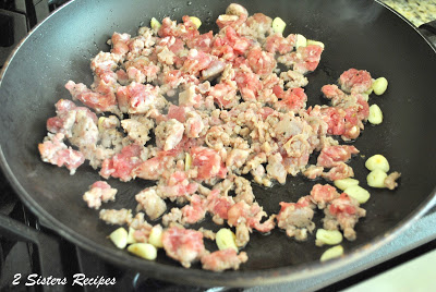 A skillet with crumbled sausages cooking on stove top. by 2sistersrecipes.com 