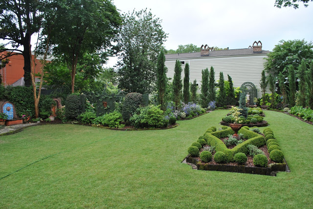 A view of a large backyard landscaped with a beautiful green garden.