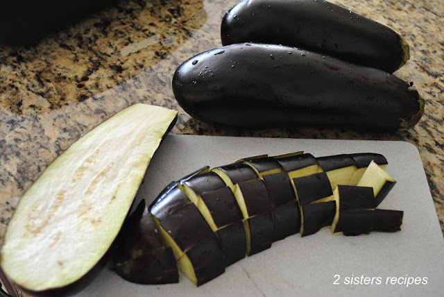 A photo of eggplant chopped on a white cutting board. by 2sistersercipes.com