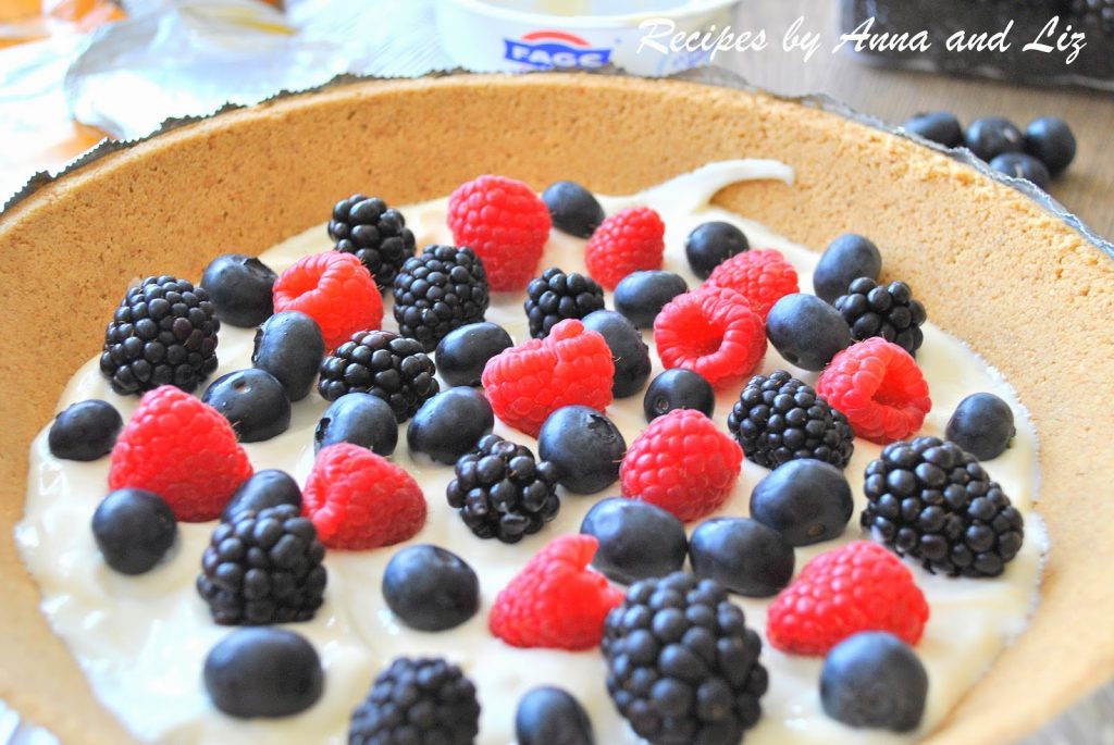 An already pie crust filled with a layer of yogurt, and topped with mixed fresh berries.