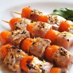 Four kabobs with chunks of tuna and cherry tomatoes.