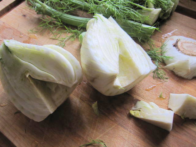 A fennel bulb on a cutting board with its' bottom and cord removed.