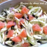 A large deep oval white bowl with sliced fennel and chunks of grapefruit and black olives.