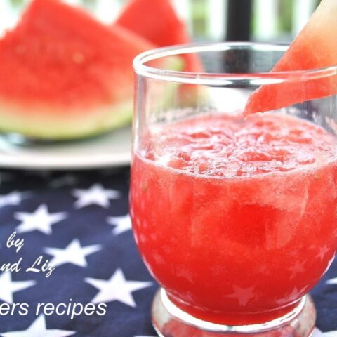 A glass of watermelon juice served with a slice of watermelon on the rim of the glass.
