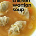 A white soup bowl filled with chicken broth and mini wontons.