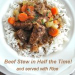 A white dinner plate with cooked rice and some beef and vegetables on top.