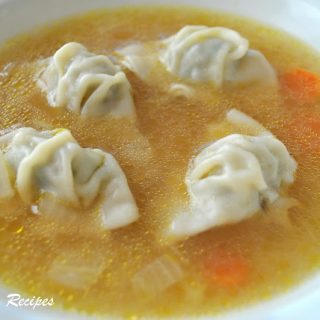 A bowl of chicken broth with mini wontons in the soup.