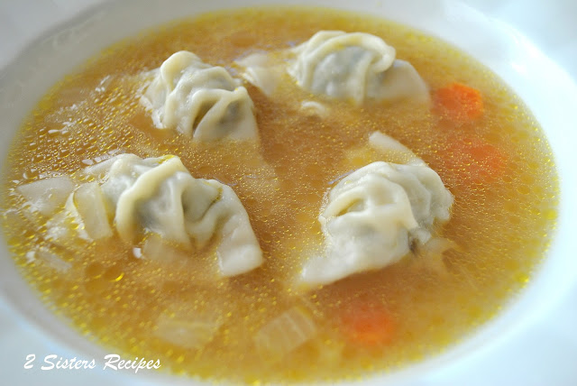 A bowl of chicken broth with mini wontons in the soup.