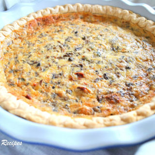 A white pie dish with an already baked quiche. by 2sistersrecipes.com