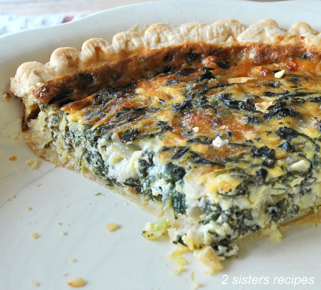 A slice of baked quiche loaded with spinach and cheese on a white plate.