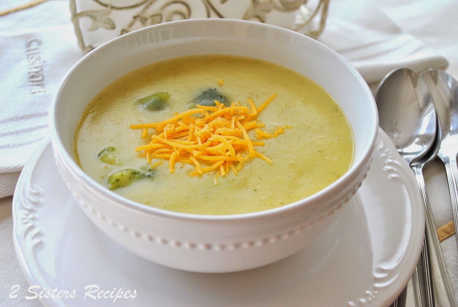 A bowl of soup with some shredded cheddar cheese on top. by 2sistersrecipes.com