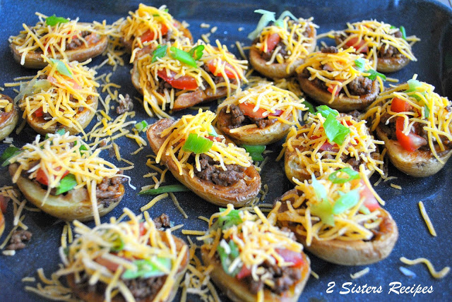 A blue baking dish filled with little potatoes filled with meat, and topped with shredded cheese and cinlantro. 