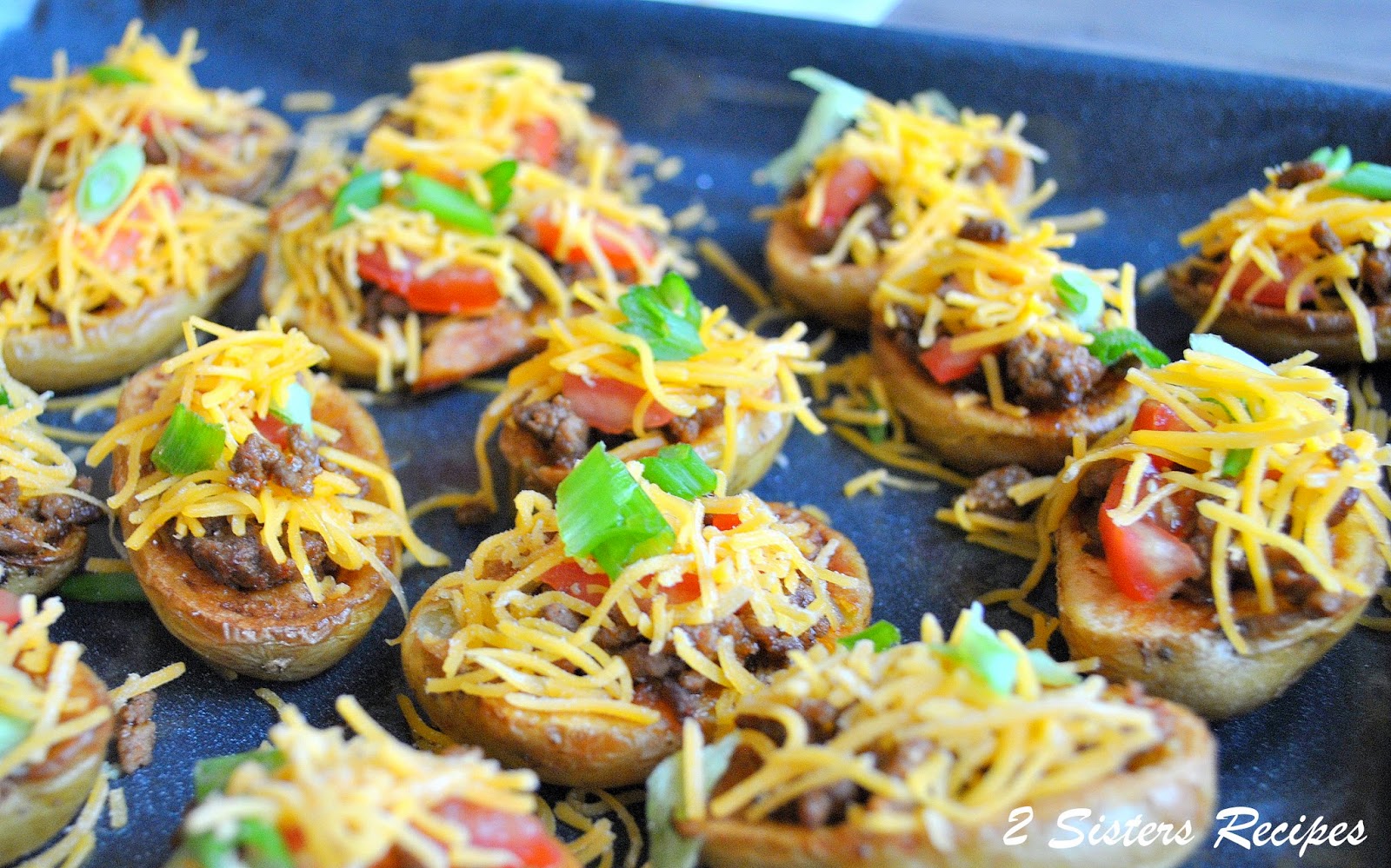 small potatoes filled with meat, shredded cheddar cheese, and cilantro on top.