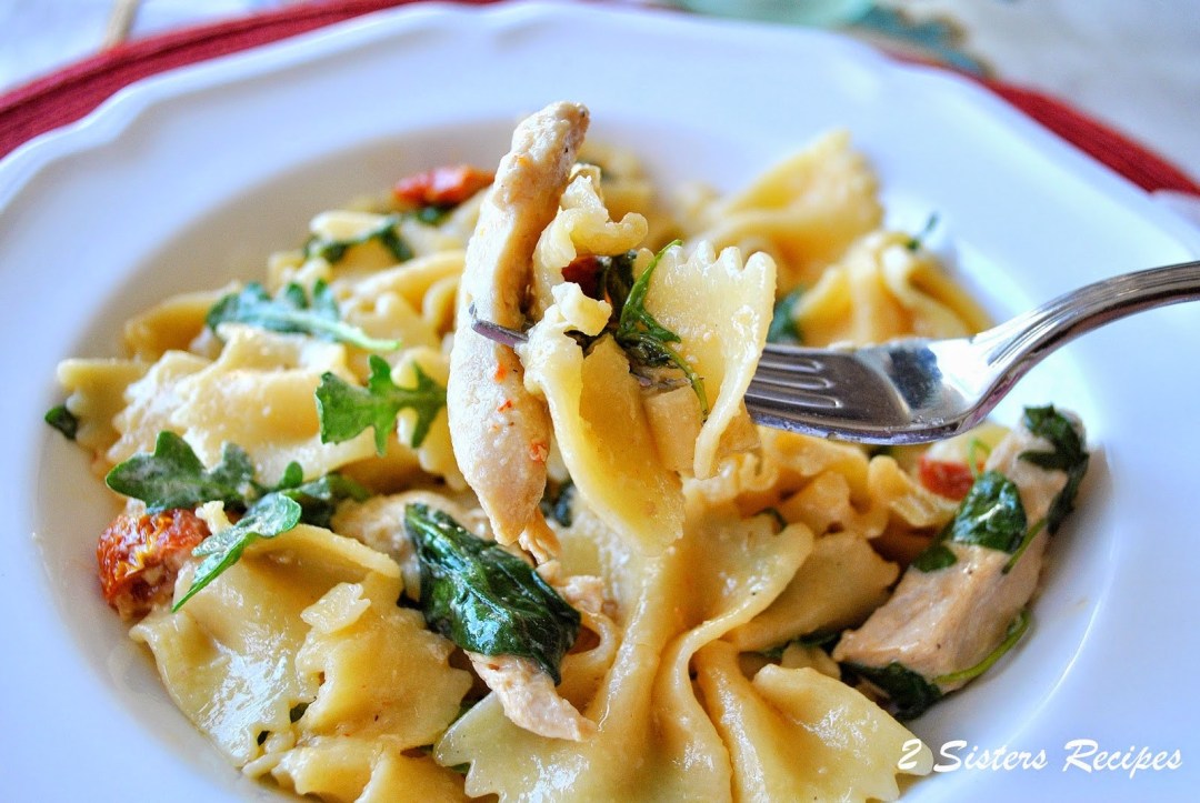 A forkful of pasta and greens in a white dish. by 2sistersrecipes.com 
