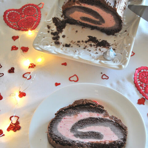 A slice of Chocolate & Strawberry Ice Cream Roll served on a white plate.