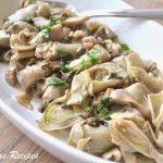 Artichoke Hearts Steamed with Olives, Capers and Garlic served in an oval white platter.