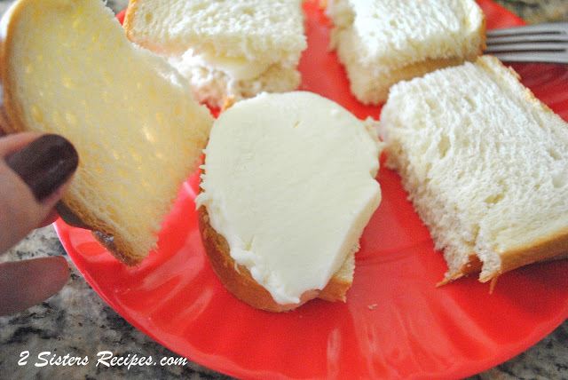 A red plate with white bread cut into quarters and a slice of mozzarella on each slice. by 2sistersrecipes.com